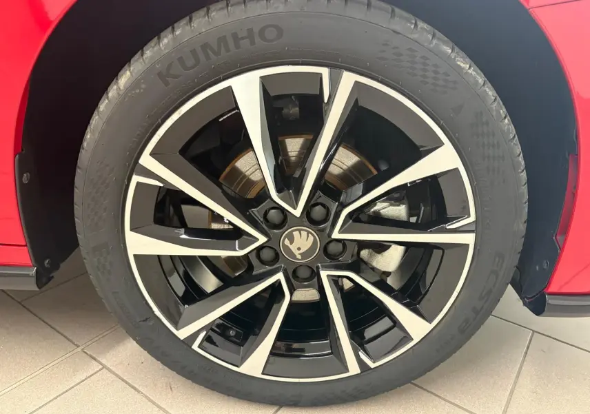 Gros plan sur la roue avant droite d’une Skoda Fabia rouge Velvet avec jante noire et argentée au design moderne.