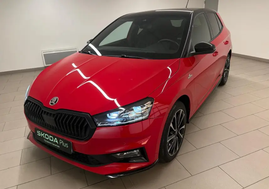 Vue 3/4 avant droite d'une Skoda Fabia Monte Carlo rouge velvet avec toit noir et jantes sport dans un showroom.
