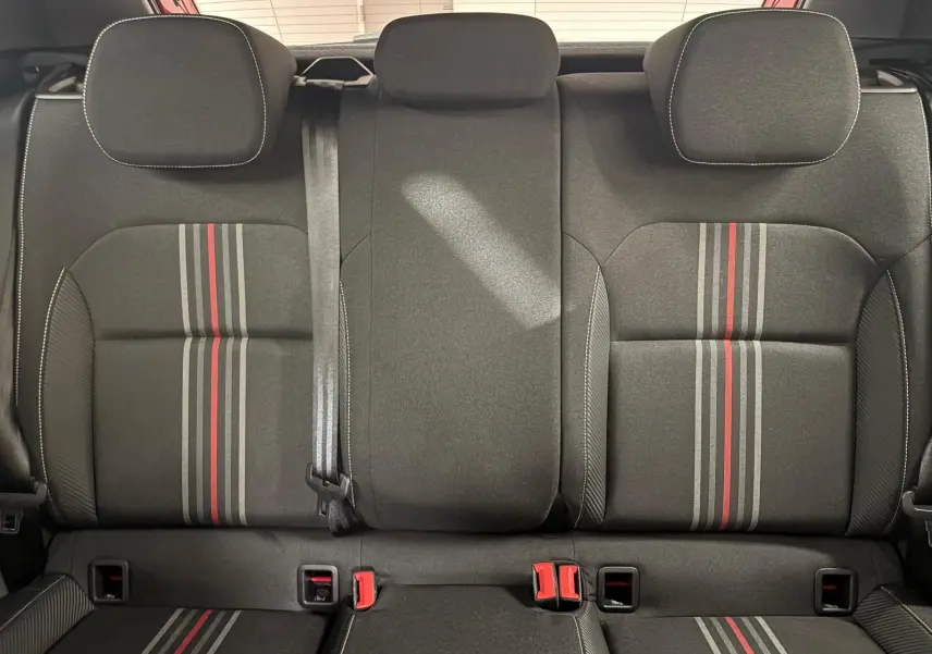Vue arrière des sièges arrière noirs avec bandes grises et rouges, appuie-têtes et ceinture de sécurité visibles dans une Skoda Fabia.
