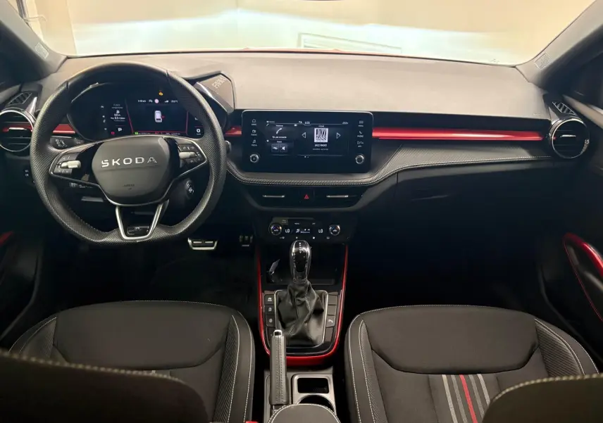 Vue intérieure avant de la Skoda Fabia Monte Carlo 2025, tableau de bord noir avec touches rouges et volant multifonction.