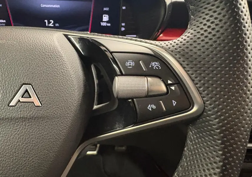 Gros plan sur les commandes à droite du volant perforé d’une Skoda Fabia 2025, avec affichage numérique en arrière-plan.