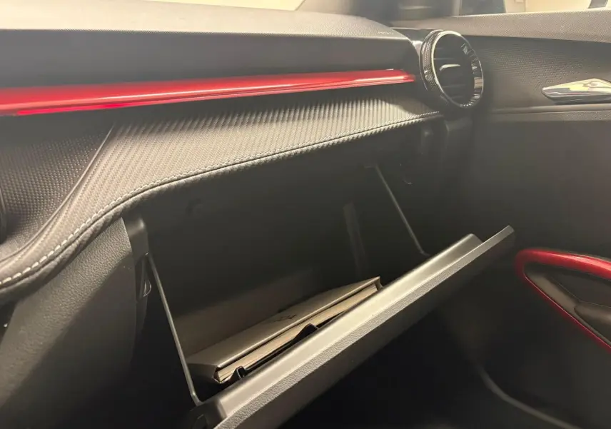 Vue intérieure côté passager du tableau de bord noir avec insert rouge et boîte à gants ouverte d'une Skoda Fabia Monte Carlo 2025.