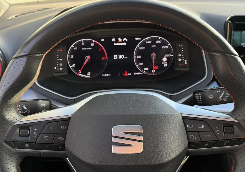 Vue rapprochée du volant cuir noir avec surpiqûres rouges et tableau de bord digital de la SEAT IBIZA TSI 115 FR 2025.