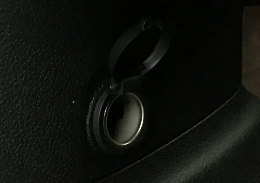 Prise allume-cigare noire ouverte dans l'habitacle du Peugeot Partner blanc 2025, vue rapprochée du détail intérieur.