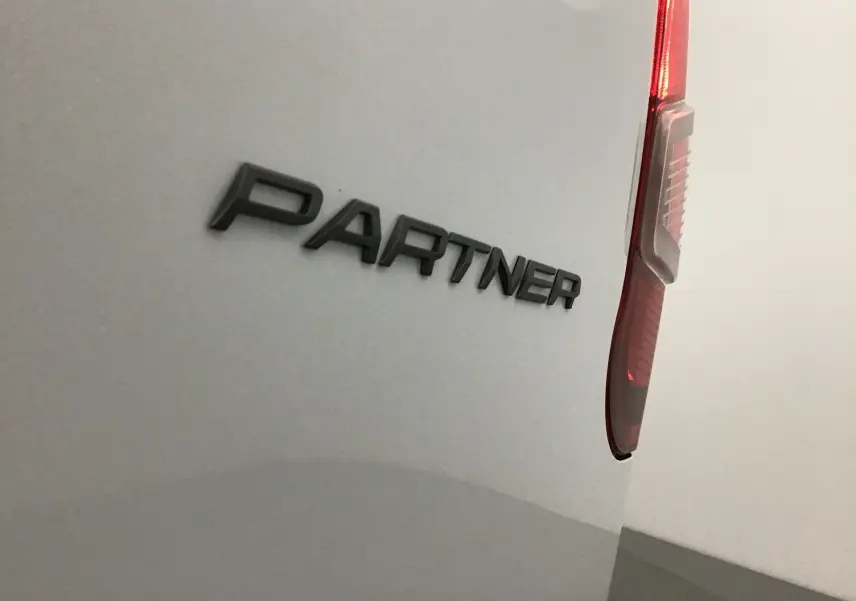 Détail arrière droit du Peugeot Partner blanc 2025 avec logo PARTNER et feu arrière vertical visible.