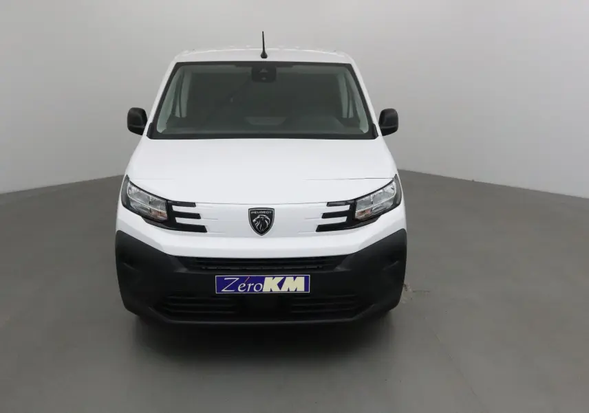Vue frontale d’un Peugeot Partner blanc 2025 avec calandre noire et logo lion central, dans un studio neutre.