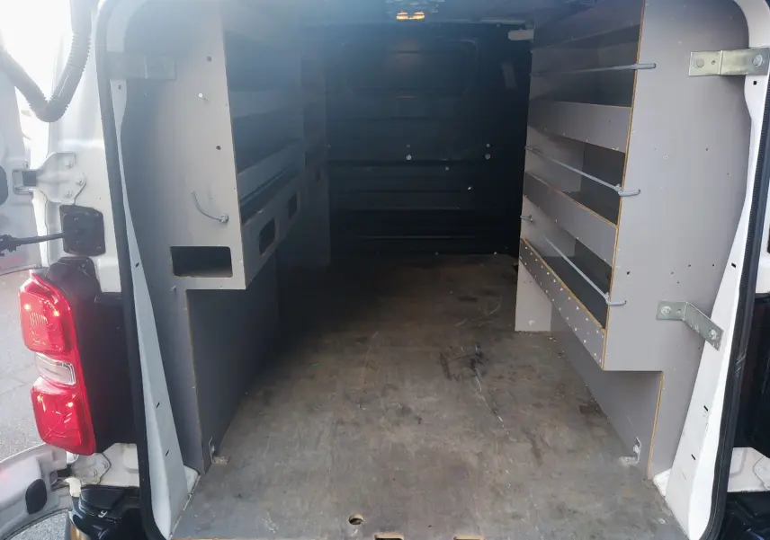 Vue arrière du fourgon blanc Citroën Jumpy 2021, montrant l'intérieur aménagé avec étagères et plancher en bois.