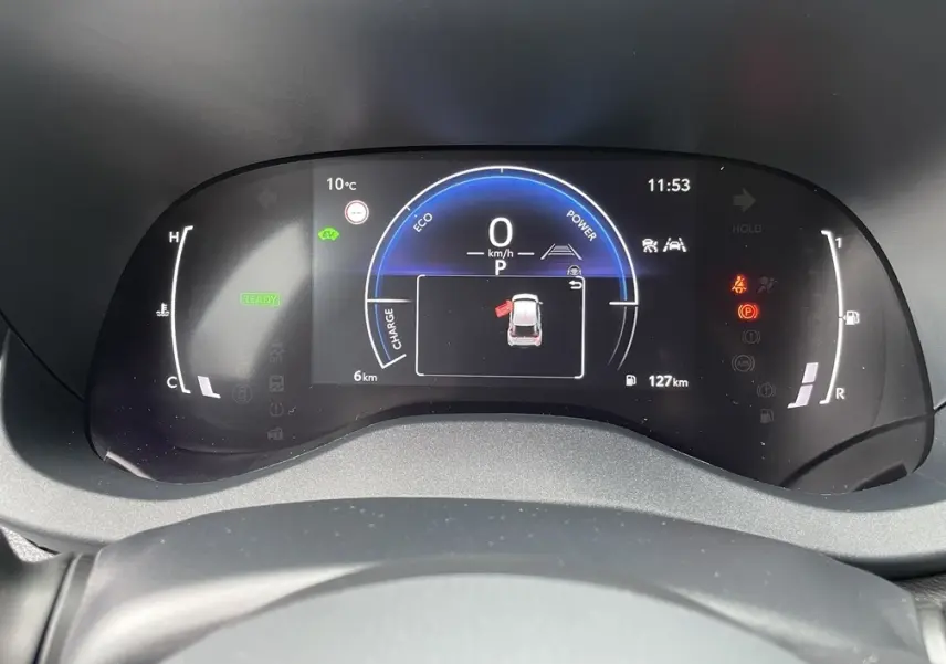 Tableau de bord numérique de la Toyota Yaris Cross 2026 affichant la vitesse, l'autonomie et les alertes en vue frontale.