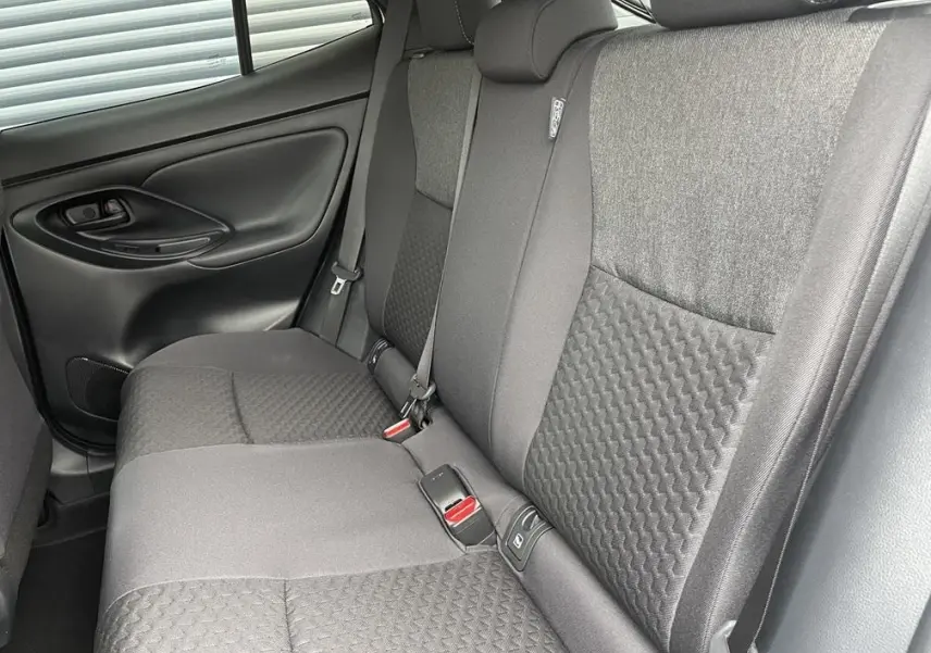 Vue intérieure côté gauche des sièges arrière gris foncé de la Toyota Yaris Cross 2026 avec ceinture de sécurité et porte.