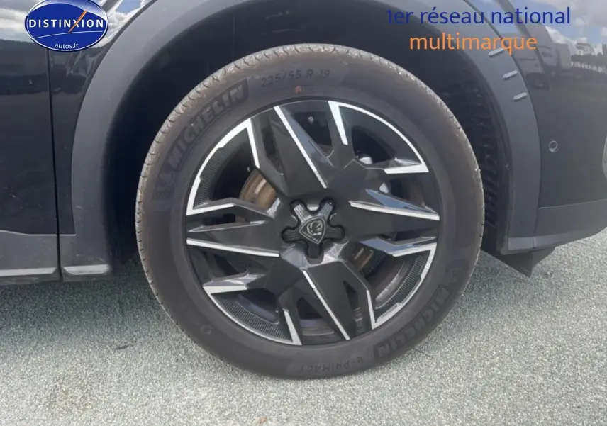 Gros plan sur la roue avant gauche noire d’un Peugeot 5008 Hybrid 145 allure e-dcs6 avec jante alu stylisée.