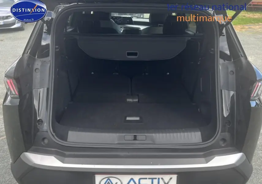 Coffre ouvert en vue arrière d’un Peugeot 5008 noir, banquette arrière rabattue et cache-bagages déployé.