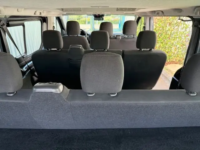 Vue intérieure arrière du Renault Trafic Combi gris comète, montrant les trois rangées de sièges avec appuie-têtes.