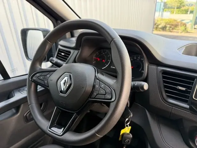 Vue intérieure centrée sur le volant noir du Renault Trafic Combi 2022 avec commandes intégrées et tableau de bord visible.