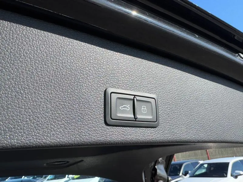 Gros plan sur les boutons d'ouverture et de verrouillage du coffre du coffre d'un Audi Q2 noir Mythic métallisé.