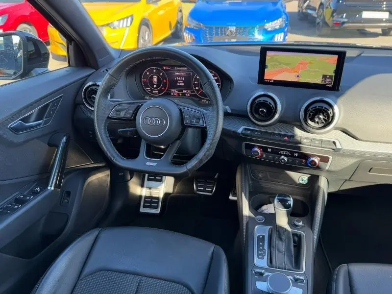 Vue intérieure avant de l'Audi Q2 30 TDI S line 2024 avec tableau de bord numérique et écran GPS couleur.