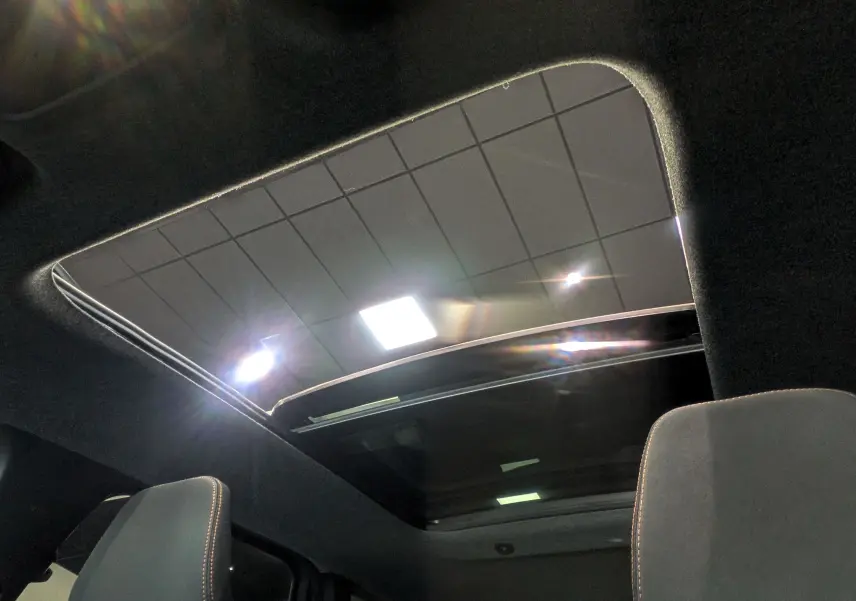 Toit panoramique ouvert vu de l'intérieur du Dacia Bigster 2026, avec ciel et éclairage intérieur visibles.