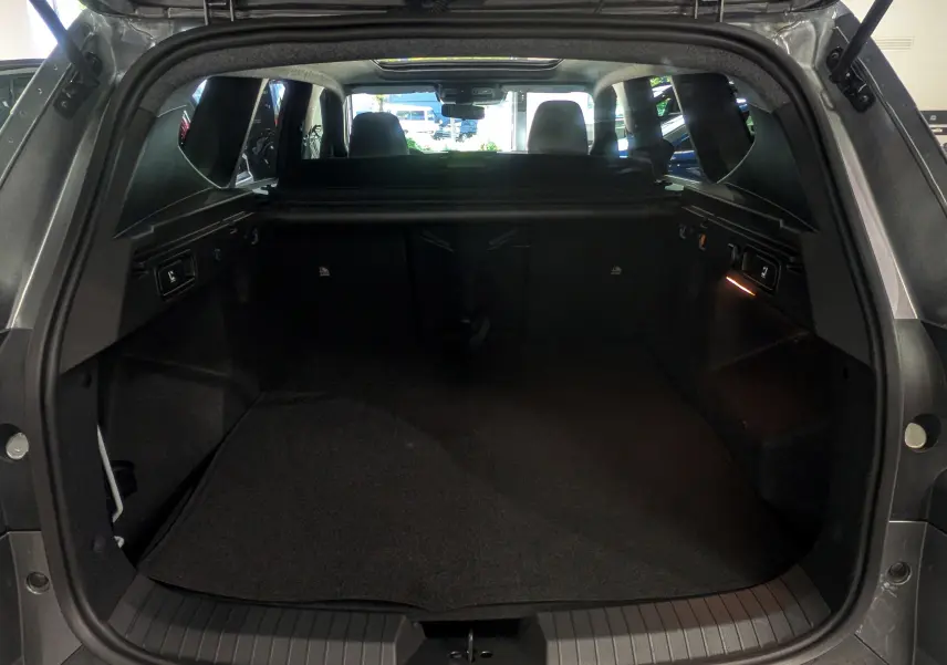 Vue intérieure du coffre ouvert du Dacia Bigster gris schiste, montrant l'espace de chargement et la banquette arrière.
