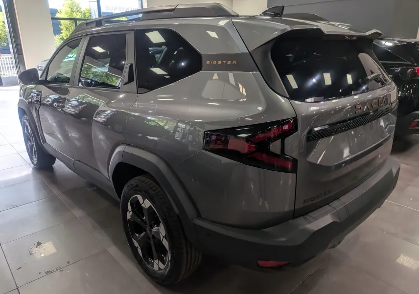 Vue 3/4 arrière droite du Dacia Bigster gris schiste avec jantes noires et logo "Bigster" sur la custode.