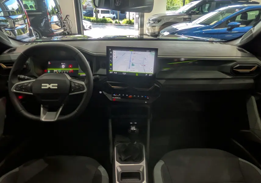 Vue intérieure avant du Dacia Bigster gris schiste 2026, avec tableau de bord numérique et écran central tactile affichant la navigation.