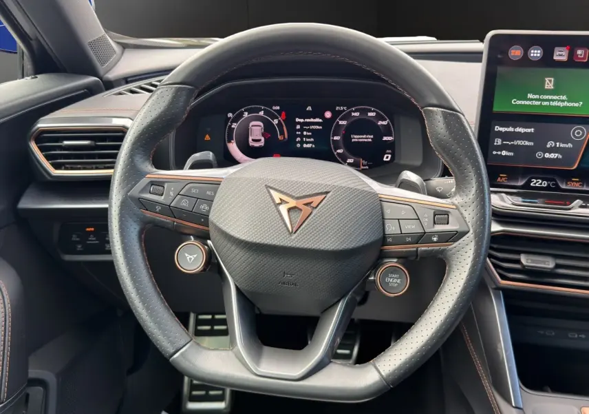 Vue centrée sur le volant cuir perforé noir avec logo CUPRA, tableau de bord numérique et écran tactile central.