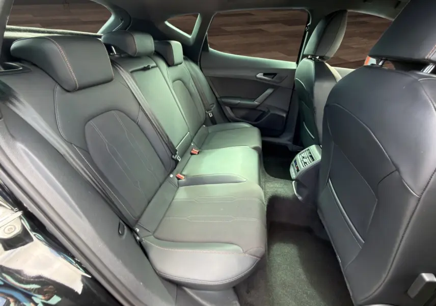 Vue intérieure arrière côté droit du CUPRA Formentor 2025 avec sièges noirs en cuir et tissu, finition soignée et console centrale.