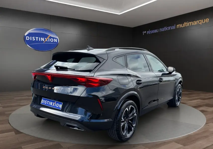 Vue 3/4 arrière droite d'une CUPRA Formentor noire avec feux arrière LED distinctifs dans un showroom.
