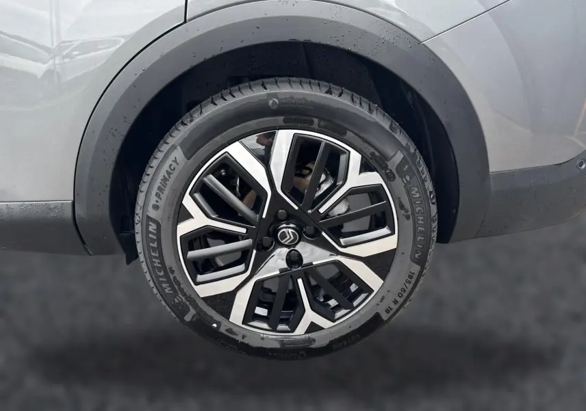Gros plan sur la roue arrière droite gris mercure d'une Citroën C4 X 1.2 hybride avec jante alu bicolore distinctive.