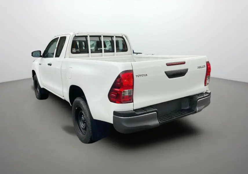 Toyota Hilux 4x4 blanc pur vu en 3/4 arrière droit, avec benne ouverte et roues noires basiques.