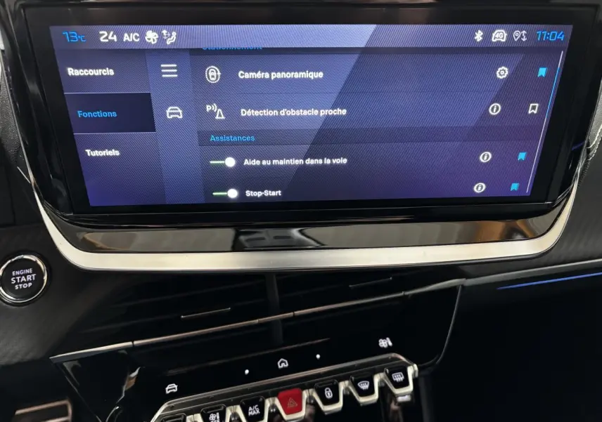 Écran tactile central affichant les aides à la conduite sur Peugeot 208 Hybrid 110 e-DCS6 GT gris clair, vue intérieure frontale.