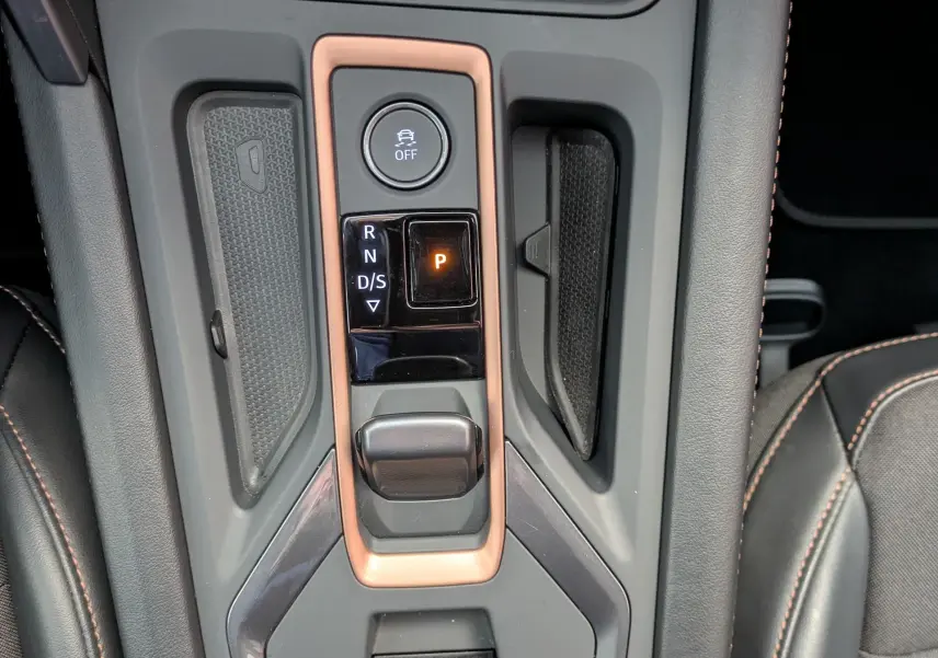 Vue rapprochée de la console centrale de la CUPRA Formentor 2.0 TDI 150 DSG7, avec levier de vitesse et surpiqûres orange sur sellerie noire.