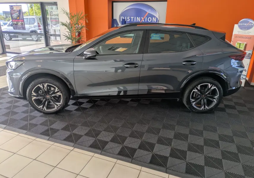 Vue de profil côté gauche d'un CUPRA Formentor gris magnétique 2025 avec jantes alliage 18'' bicolores en showroom.