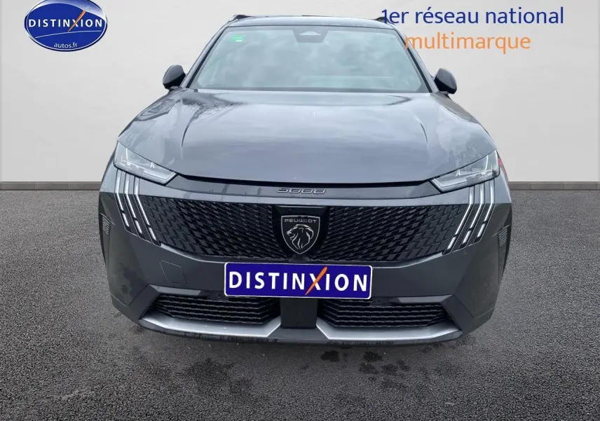 Vue avant du Peugeot 5008 Hybrid gris titane avec calandre noire et feux LED distinctifs en griffes.