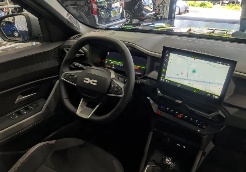 Vue intérieure côté conducteur du Dacia Bigster bleu indigo 2026, avec tableau de bord numérique et écran tactile central.