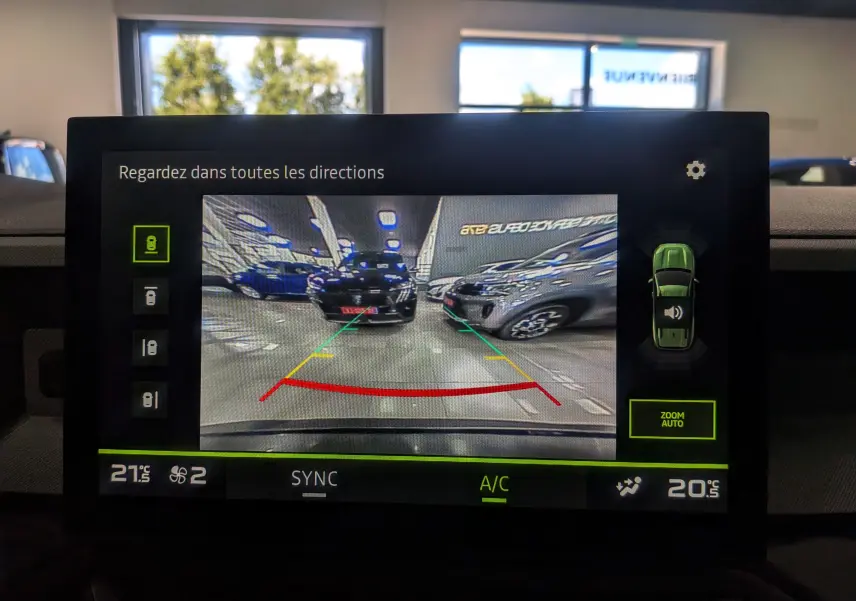 Vue écran caméra de recul du Dacia Bigster Bleu Indigo, affichant les lignes de guidage et l'environnement du parking intérieur.
