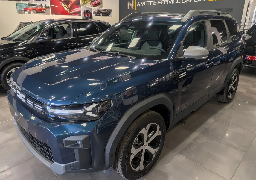 Dacia Bigster bleu indigo en vue 3/4 avant droit, avec jantes bicolores et détails noirs contrastants.