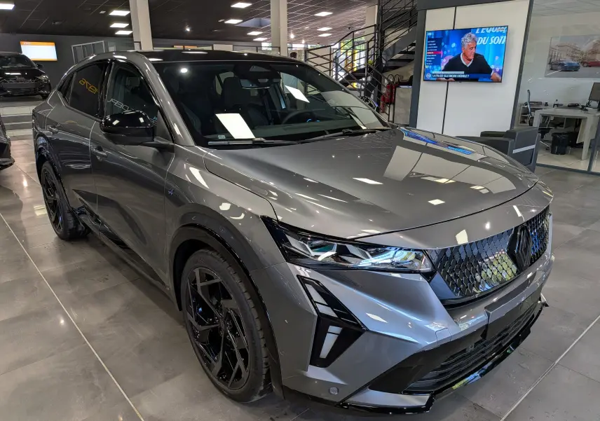 Renault Rafale hyper hybrid gris schiste en 3/4 avant droit, avec calandre noire et jantes noires distinctives.