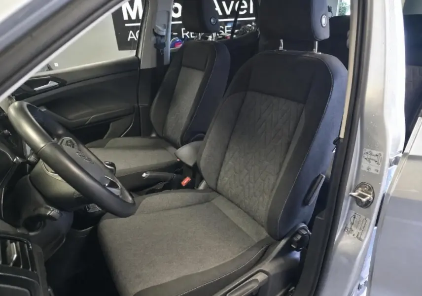 Vue intérieure côté conducteur du Volkswagen T-Cross gris 2025, montrant les sièges en tissu et le volant multifonction en cuir.