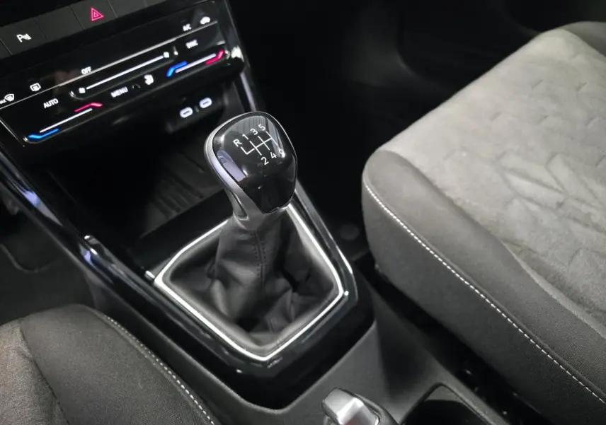 Gros plan sur le levier de vitesses manuel noir et la console centrale du Volkswagen T-Cross gris, siège tissu visible.