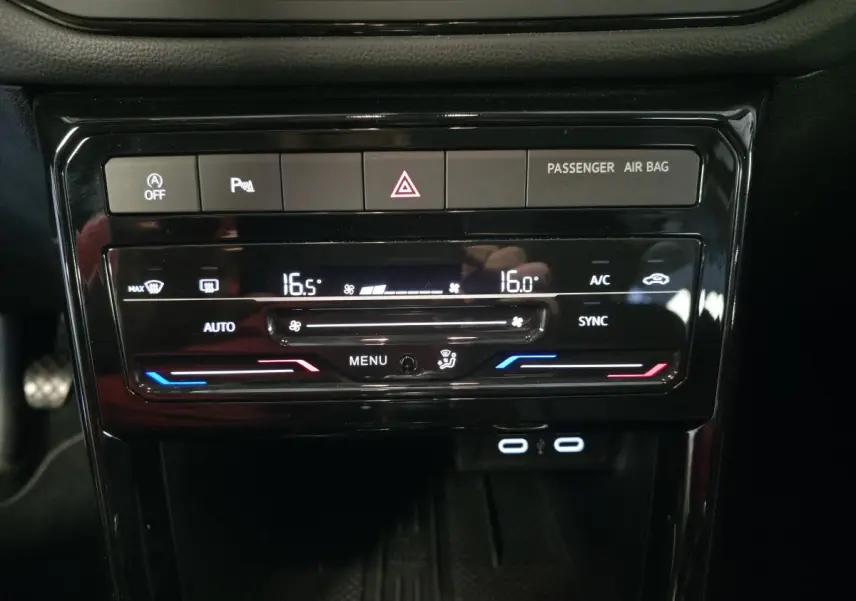 Vue rapprochée du tableau de bord du Volkswagen T-Cross gris, affichant la climatisation automatique bi-zone et ports USB-C.