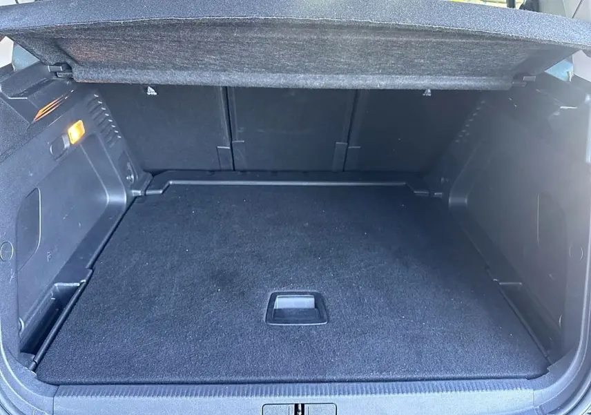Coffre ouvert vu de l'arrière d'un Citroën C5 Aircross noir 2025, espace de chargement vide avec tapis noir.