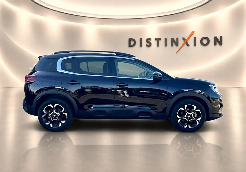 Profil côté gauche d'un Citroën C5 Aircross noir 2025 avec jantes alu et barres de toit en showroom.