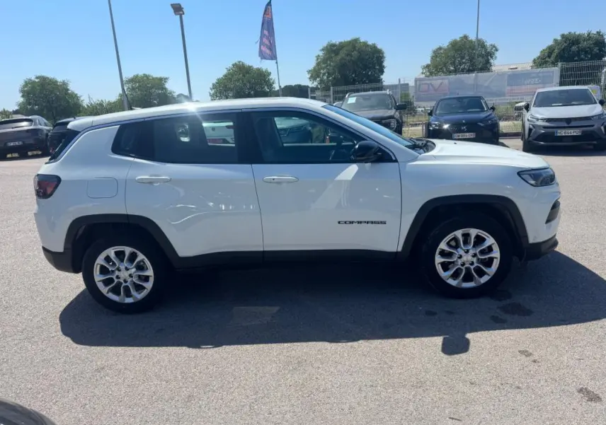 Vue latérale droite d'un Jeep Compass blanc 2025, avec jantes alliage et logo "Compass" visible sur la porte.