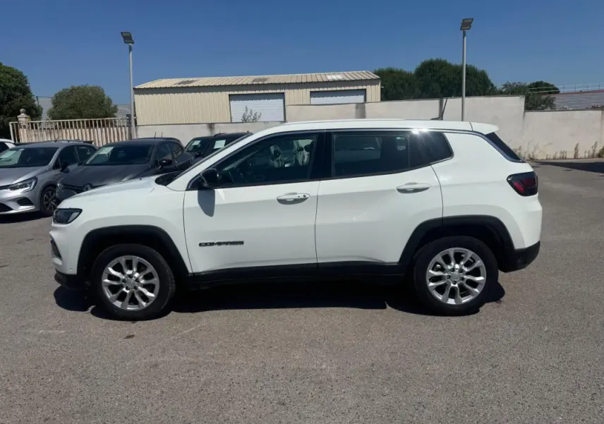 Jeep Compass blanc vu de profil côté gauche, avec jantes alliage et détails noirs contrastants.