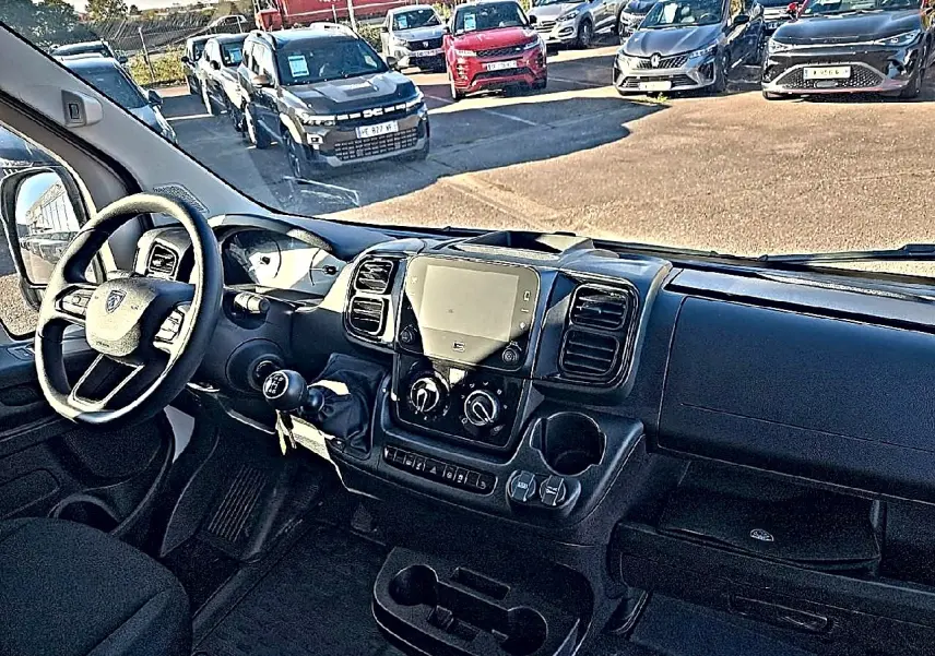 Vue intérieure côté conducteur du Peugeot Boxer Fourgon blanc, montrant le tableau de bord avec écran tactile et volant multifonction.
