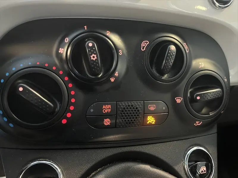 Détail du tableau de bord noir de la FIAT 500 blanche 2021 montrant les commandes de climatisation et ventilation.