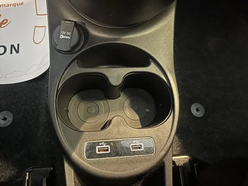 Gros plan sur la console centrale de la FIAT 500 blanche 2021, montrant porte-gobelets, prise 12V et deux ports USB.