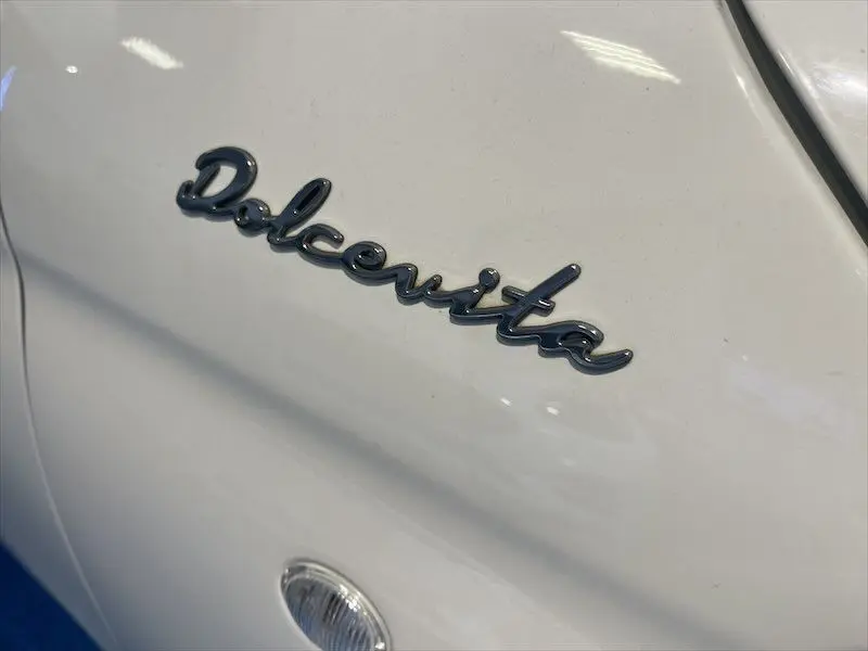 Gros plan sur l’inscription Dolcevita en chrome sur la carrosserie blanche d’une FIAT 500 hybride 2021.