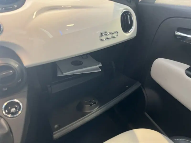 Intérieur de la Fiat 500 blanc, vue côté passager sur la boîte à gants ouverte et tableau de bord avec logo 500.