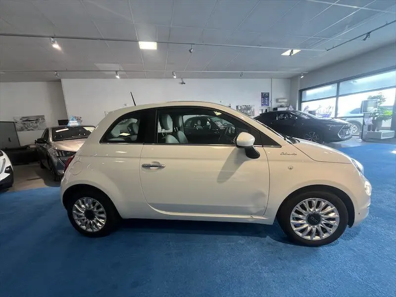 Profil côté gauche d'une FIAT 500 blanche DolceVita 2021, avec jantes alliage et intérieur clair visible.