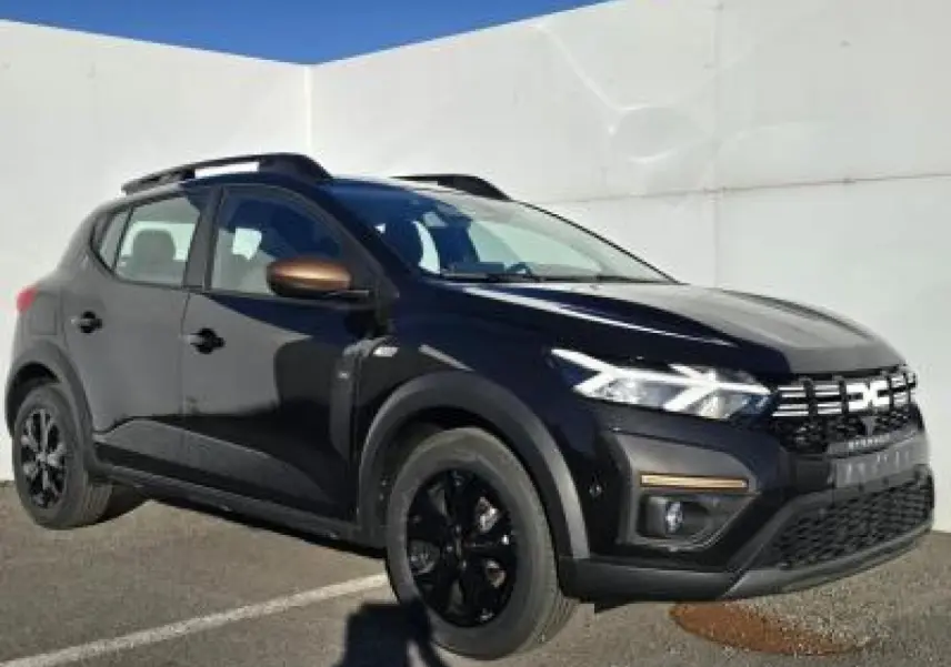 Dacia Sandero III Stepway noir nacré vue 3/4 avant droit avec barres de toit et jantes noires distinctives.